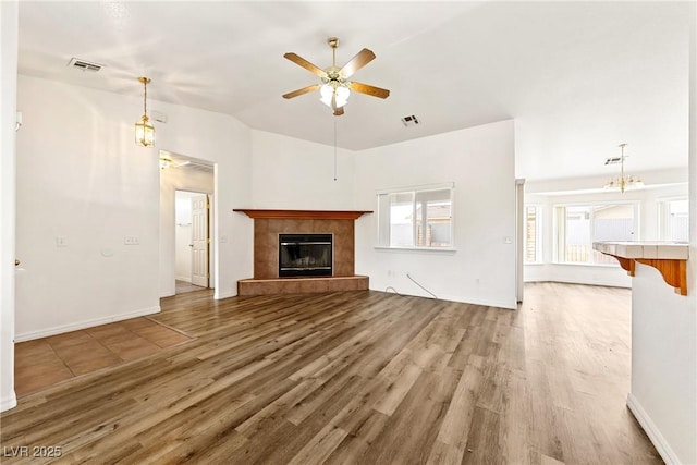 654 Mazelle Ln, Pahrump, NV 89060 - unfurnished living room featuring a ceiling fan, wood finished floors, a tile fireplace, baseboards, and a chandelier