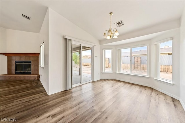 654 Mazelle Ln, Pahrump, NV 89060 - unfurnished dining area with a chandelier, wood finished floors, vaulted ceiling, a tile fireplace, and baseboards