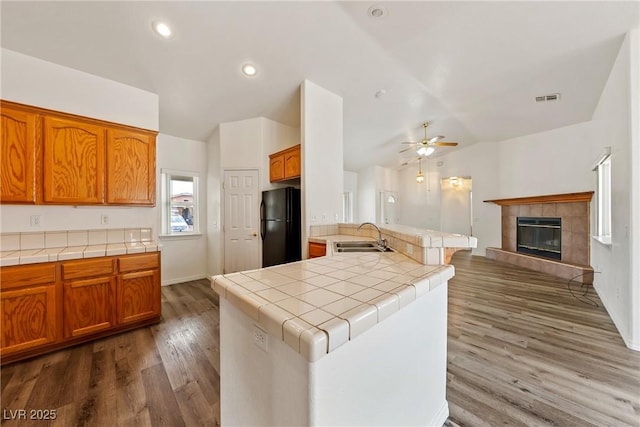 654 Mazelle Ln, Pahrump, NV 89060 - kitchen with freestanding refrigerator, a sink, vaulted ceiling, tile countertops, and ceiling fan