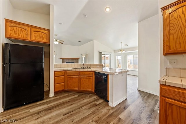 654 Mazelle Ln, Pahrump, NV 89060 - kitchen featuring black appliances, a sink, vaulted ceiling, a peninsula, and light wood-type flooring