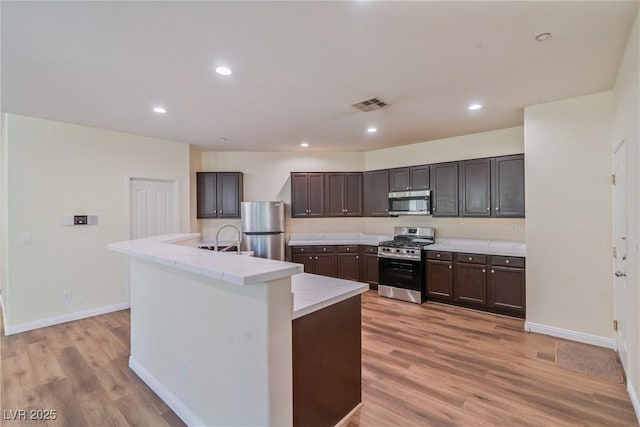 2037 Brush Stroke St, Henderson, NV 89044 - kitchen with stainless steel appliances, a sink, light wood-type flooring, dark brown cabinets, and recessed lighting