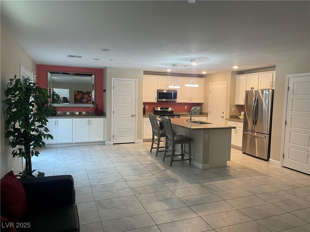 330 Silva Pl, Henderson, NV 89011 - kitchen with appliances with stainless steel finishes, light tile patterned floors, a sink, white cabinetry, and recessed lighting