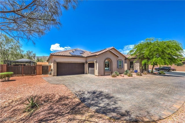 10319 Larkmead Ave, Las Vegas, NV 89149 - mediterranean / spanish-style house featuring decorative driveway, a garage, stucco siding, and solar panels