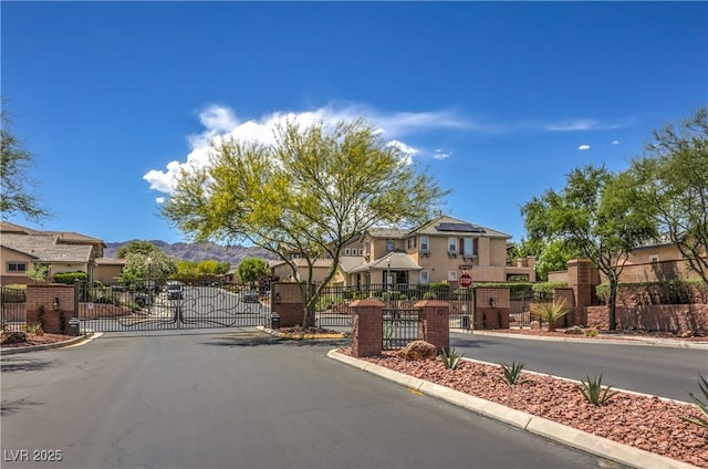 10319 Larkmead Ave, Las Vegas, NV 89149 - view of asphalt street with a gate, traffic signs, a residential view, curbs, and a gated entry