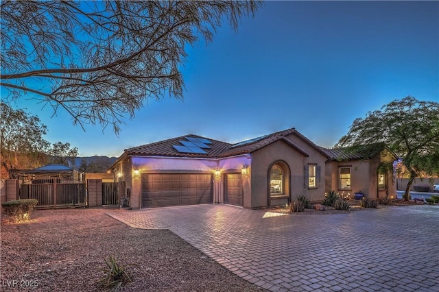 10319 Larkmead Ave, Las Vegas, NV 89149 - mediterranean / spanish-style house featuring a garage, stucco siding, decorative driveway, solar panels, and a tiled roof