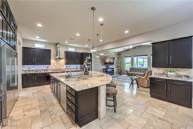 10319 Larkmead Ave, Las Vegas, NV 89149 - kitchen with wall chimney exhaust hood, open floor plan, backsplash, stone tile floors, and recessed lighting