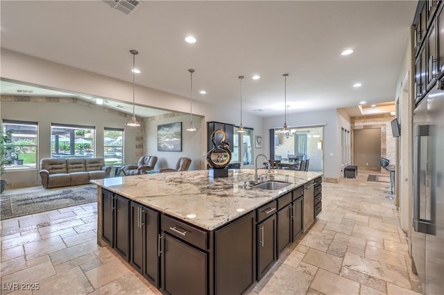 10319 Larkmead Ave, Las Vegas, NV 89149 - kitchen featuring a sink, stone tile flooring, recessed lighting, dark brown cabinets, and a kitchen island with sink