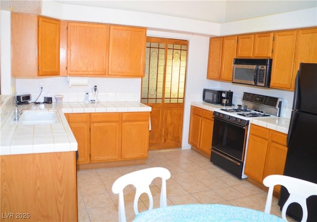 3519 W Red Coach Ave, North Las Vegas, NV 89031 - kitchen with black appliances, a sink, tile countertops, and light tile patterned floors