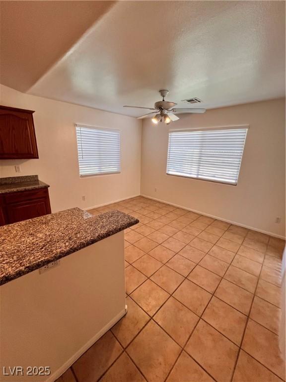 7255 W La Madre Way, Las Vegas, NV 89149 - kitchen featuring ceiling fan, light tile patterned flooring, dark stone counters, and baseboards