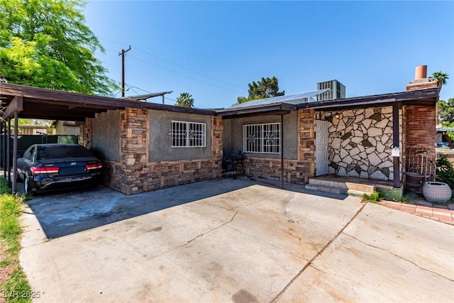 201 Cervantes St, Las Vegas, NV 89101 - view of front facade featuring driveway, a carport, stone siding, a chimney, and central AC unit