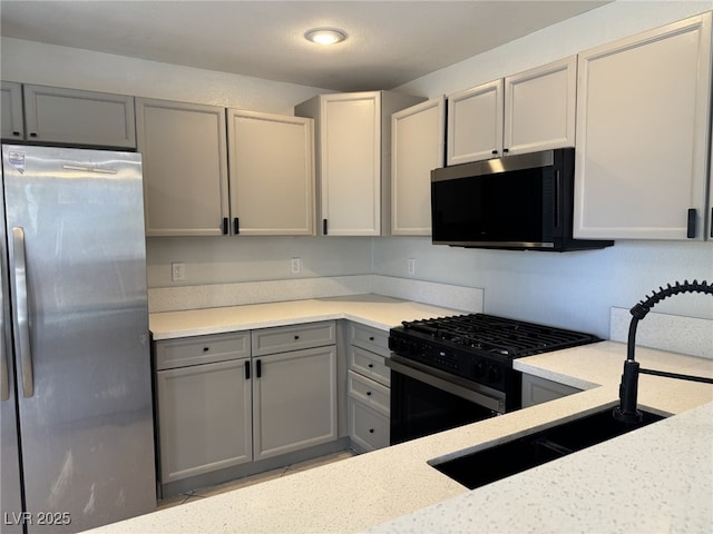 11029 Meadow Leaf Ave, Las Vegas, NV 89144 - kitchen with freestanding refrigerator, gray cabinets, black gas range, light stone countertops, and a sink
