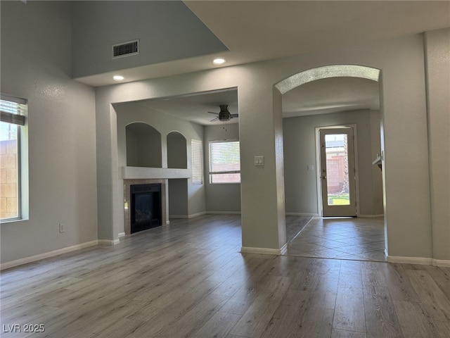 11029 Meadow Leaf Ave, Las Vegas, NV 89144 - unfurnished living room with arched walkways, wood finished floors, a tile fireplace, baseboards, and recessed lighting