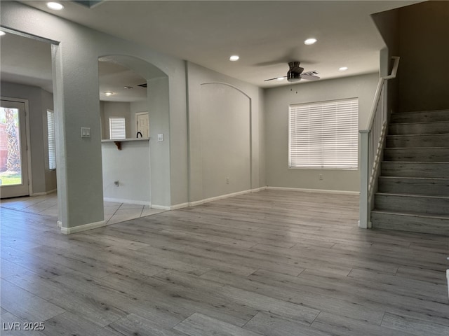 11029 Meadow Leaf Ave, Las Vegas, NV 89144 - unfurnished living room with ceiling fan, arched walkways, wood finished floors, stairs, and baseboards