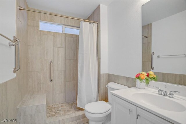 236 Dog Leg Dr, Las Vegas, NV 89148 - bathroom with a tile shower, toilet, vanity, and a wainscoted wall
