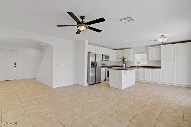 236 Dog Leg Dr, Las Vegas, NV 89148 - kitchen featuring appliances with stainless steel finishes, a sink, arched walkways, dark countertops, and ceiling fan