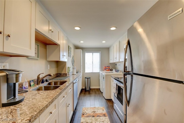 745 N Royal Crest Cir Unit 127, Las Vegas, NV 89169 - kitchen featuring appliances with stainless steel finishes, washing machine and clothes dryer, a sink, white cabinets, and baseboards