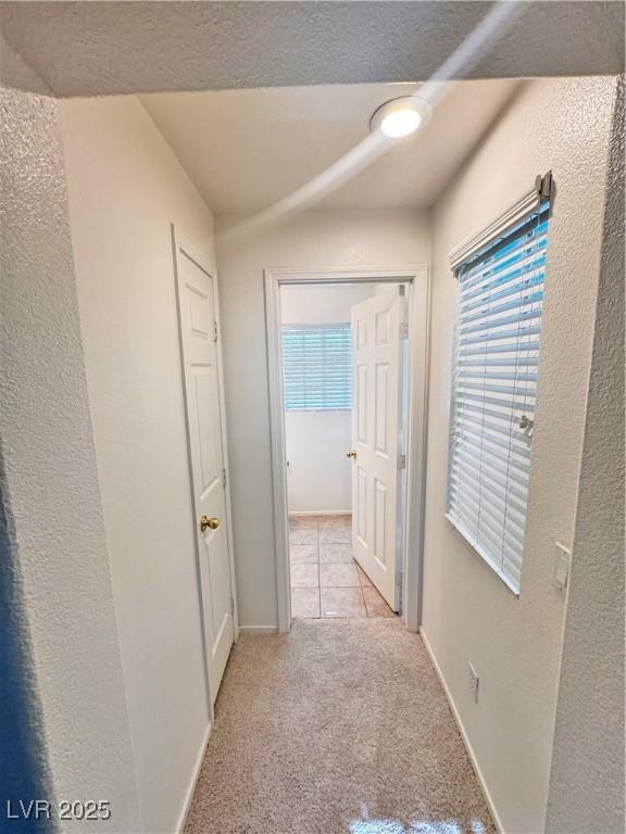 5653 Mount Athos St, North Las Vegas, NV 89031 - corridor with light colored carpet, baseboards, and light tile patterned flooring