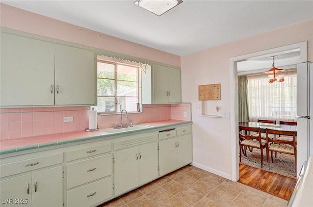 557 6th St, Boulder City, NV 89005 - kitchen with a sink, a chandelier, decorative backsplash, baseboards, and freestanding refrigerator
