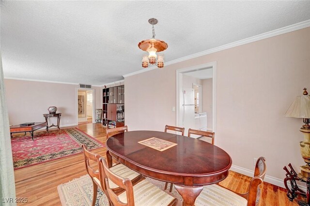 557 6th St, Boulder City, NV 89005 - dining area featuring light wood finished floors, a textured ceiling, baseboards, and crown molding