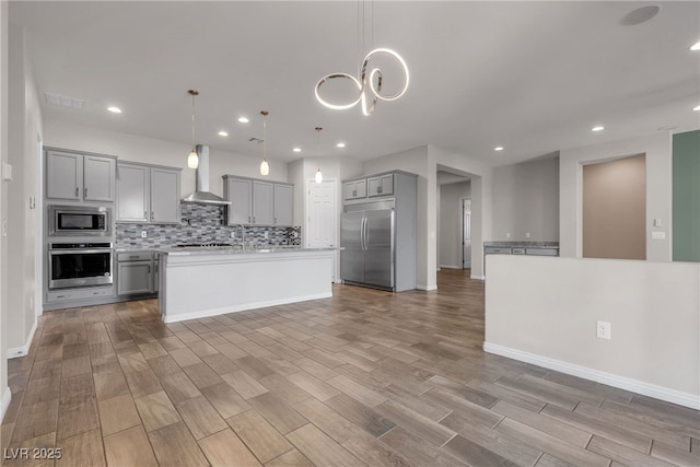 7072 Arabian Ridge St, Las Vegas, NV 89131 - kitchen with built in appliances, gray cabinets, wall chimney range hood, light wood-type flooring, and decorative backsplash