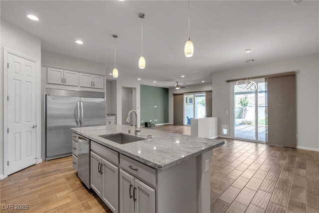 7072 Arabian Ridge St, Las Vegas, NV 89131 - kitchen featuring a sink, stainless steel appliances, light wood-type flooring, light stone countertops, and decorative light fixtures