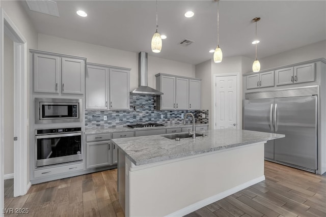 7072 Arabian Ridge St, Las Vegas, NV 89131 - kitchen featuring built in appliances, wall chimney range hood, a sink, wood finished floors, and tasteful backsplash