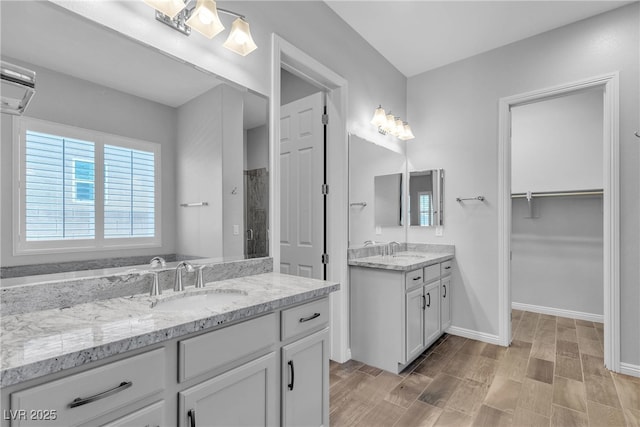 7072 Arabian Ridge St, Las Vegas, NV 89131 - full bathroom with tiled shower, two vanities, wood finished floors, baseboards, and a spacious closet