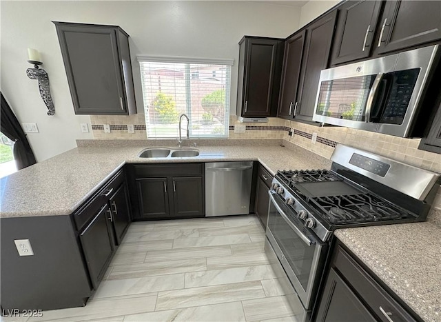 8682 Gateway Glen Dr, Las Vegas, NV 89178 - kitchen featuring appliances with stainless steel finishes, a sink, tasteful backsplash, light marble finish floors, and a peninsula