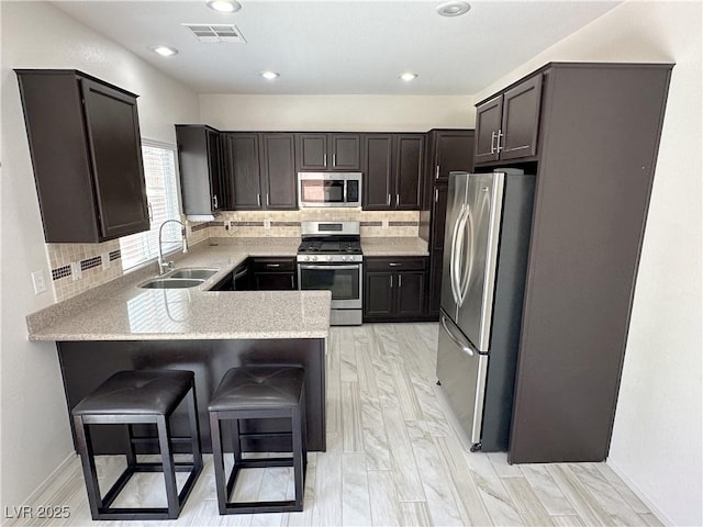 8682 Gateway Glen Dr, Las Vegas, NV 89178 - kitchen featuring appliances with stainless steel finishes, a sink, a peninsula, tasteful backsplash, and recessed lighting
