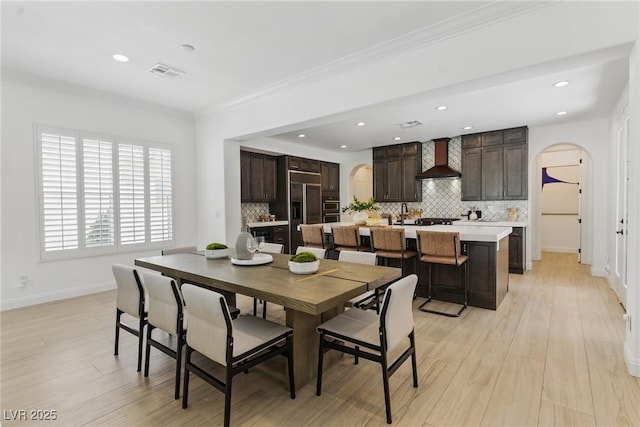 11775 Woodbrook Ct, Las Vegas, NV 89141 - dining space featuring arched walkways, light wood finished floors, baseboards, recessed lighting, and ornamental molding