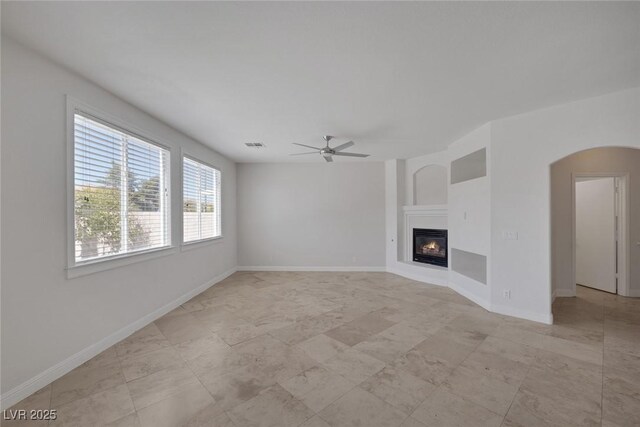 829 Dancing Vines Ave, Las Vegas, NV 89183 - unfurnished living room with a ceiling fan, arched walkways, a glass covered fireplace, and baseboards