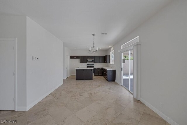 829 Dancing Vines Ave, Las Vegas, NV 89183 - kitchen with appliances with stainless steel finishes, a chandelier, light countertops, baseboards, and a center island