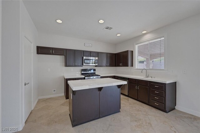 829 Dancing Vines Ave, Las Vegas, NV 89183 - kitchen featuring appliances with stainless steel finishes, a center island, dark brown cabinets, a sink, and tile countertops