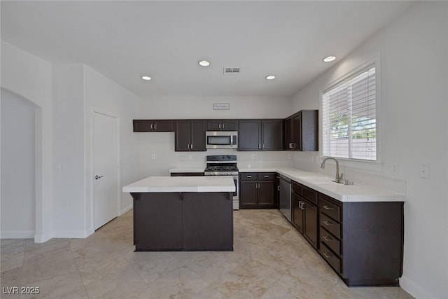 829 Dancing Vines Ave, Las Vegas, NV 89183 - kitchen featuring stainless steel appliances, a sink, dark brown cabinetry, light countertops, and a center island