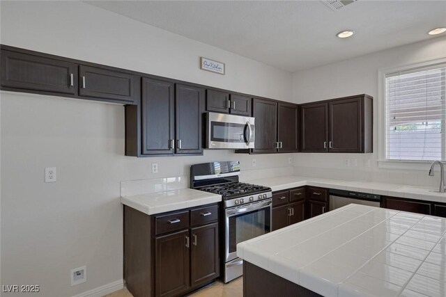 829 Dancing Vines Ave, Las Vegas, NV 89183 - kitchen with appliances with stainless steel finishes, a sink, dark brown cabinetry, recessed lighting, and baseboards