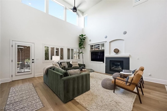 11340 Espadrille Ct, Las Vegas, NV 89138 - living room with a high ceiling, wood finished floors, plenty of natural light, baseboards, and a tiled fireplace