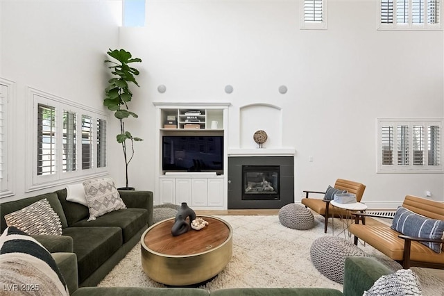 11340 Espadrille Ct, Las Vegas, NV 89138 - living room with a towering ceiling, built in shelves, a glass covered fireplace, and wood finished floors