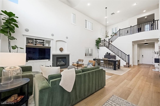 11340 Espadrille Ct, Las Vegas, NV 89138 - living area with stairs, a towering ceiling, light wood-style flooring, recessed lighting, and a glass covered fireplace