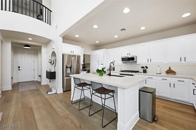 11340 Espadrille Ct, Las Vegas, NV 89138 - kitchen with appliances with stainless steel finishes, a sink, a kitchen bar, light wood-style floors, and white cabinets