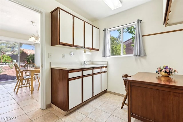 3013 Sungold Dr, Las Vegas, NV 89134 - kitchen with white cabinetry, light countertops, a chandelier, baseboards, and a sink