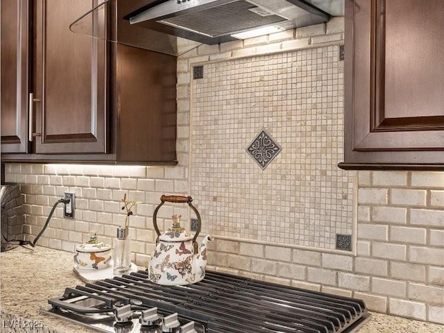 2400 Trissino Ct, Henderson, NV 89044 - kitchen featuring backsplash, under cabinet range hood, stainless steel gas stovetop, and dark brown cabinets