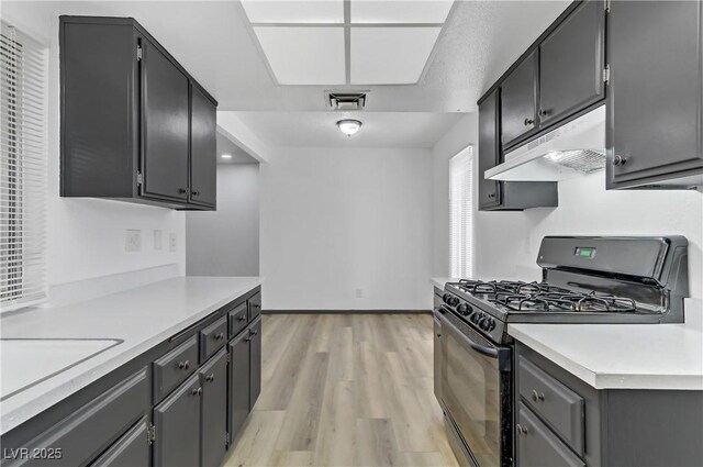 1390 Vegas Valley Dr Unit 26, Las Vegas, NV 89169 - kitchen with black gas range, under cabinet range hood, light wood-style floors, light countertops, and baseboards