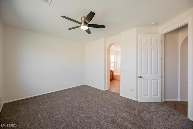 909 Trinity Pond Cir, Henderson, NV 89002 - unfurnished bedroom featuring arched walkways, carpet, baseboards, a ceiling fan, and ensuite bath