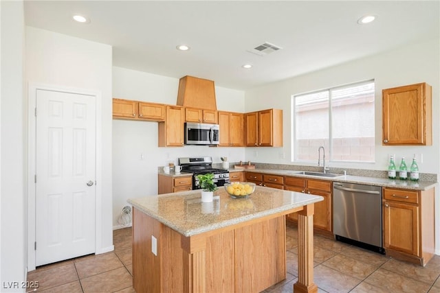 909 Trinity Pond Cir, Henderson, NV 89002 - kitchen with appliances with stainless steel finishes, a sink, a kitchen island, light stone countertops, and light tile patterned flooring