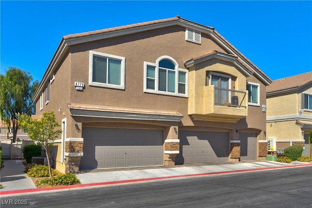 4779 Straight Flush Dr Unit 103, Las Vegas, NV 89122 - townhome / multi-family property featuring stucco siding, a garage, stone siding, and a balcony