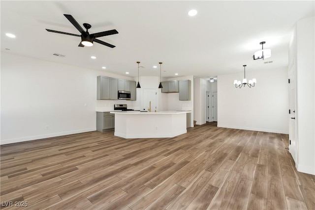 4779 Straight Flush Dr Unit 103, Las Vegas, NV 89122 - kitchen with open floor plan, appliances with stainless steel finishes, gray cabinets, light wood-style floors, and a chandelier