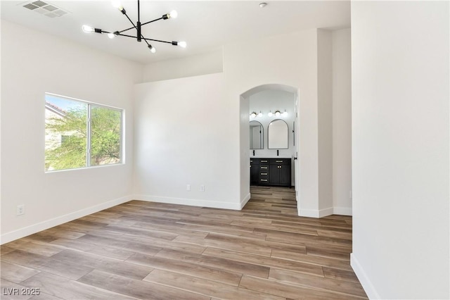 4779 Straight Flush Dr Unit 103, Las Vegas, NV 89122 - empty room with a chandelier, arched walkways, light wood-style floors, and baseboards