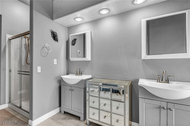 4005 Poppy Fields Dr, Las Vegas, NV 89129 - bathroom featuring two vanities, a shower stall, tile patterned floors, a textured wall, and baseboards