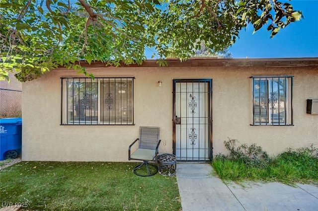 4 Britz Cir, North Las Vegas, NV 89030 - view of exterior entry featuring stucco siding and a yard