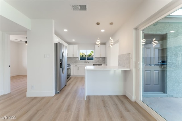 2180 Palora Ave, Las Vegas, NV 89169 - kitchen featuring stainless steel appliances, light wood-style flooring, light countertops, a peninsula, and decorative backsplash